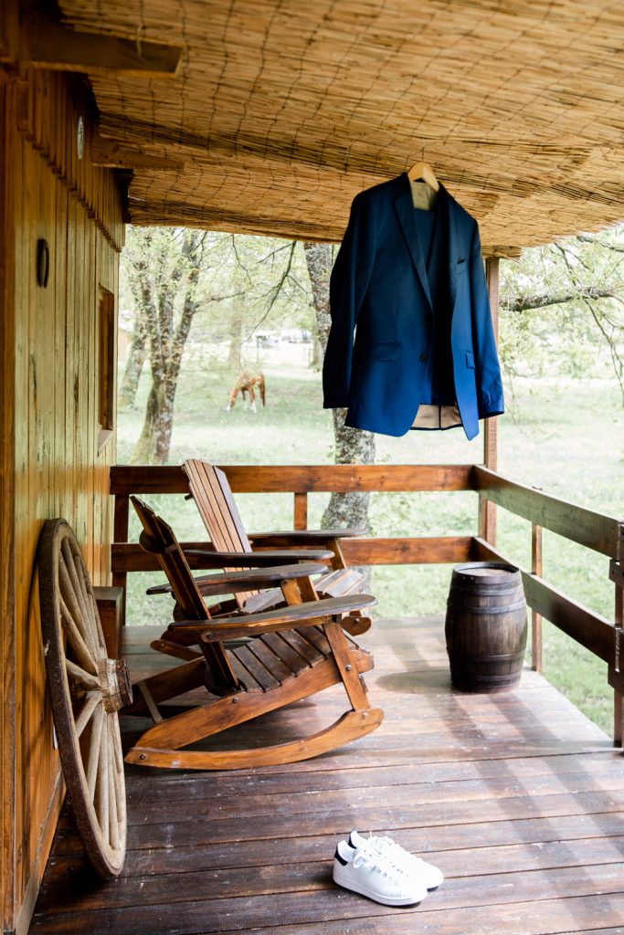 Costume de marié bleu suspendu sur une terrasse en bois avec chaussures blanches