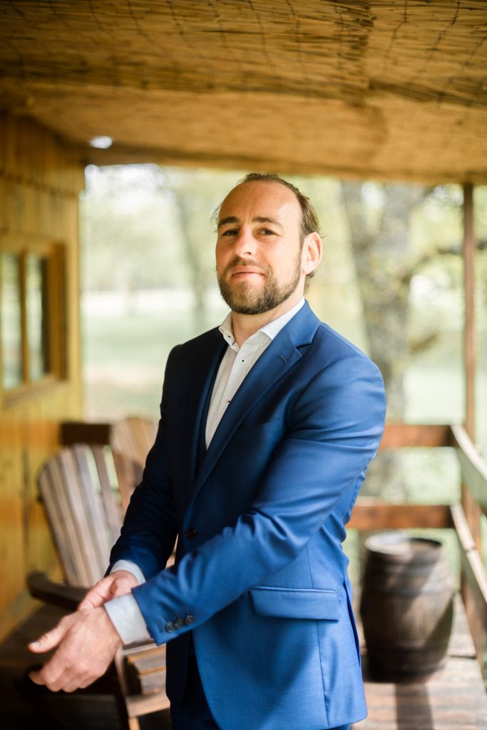 Portrait du marié en costume bleu sur une terrasse en bois