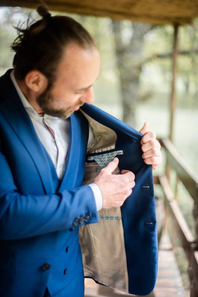 Marié regardant la doublure intérieure de sa veste de costume bleu