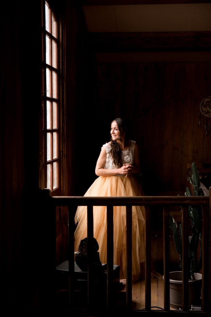 Mariée souriante en robe de mariage dans une pièce en bois