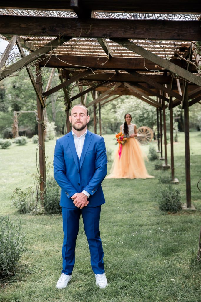 Marié les yeux fermés attendant sa mariée sous une pergola en bois mariage Landes