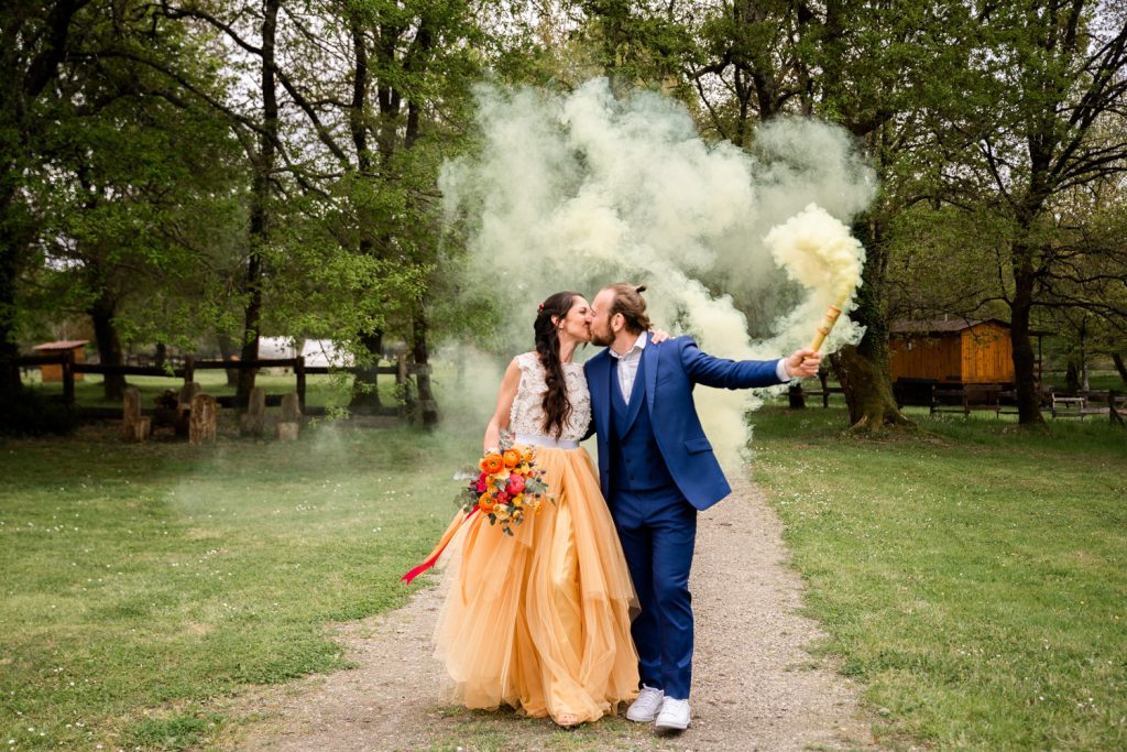 Mariés marchant en s’embrassant avec fumigène coloré lors d’un mariage dans les Landes