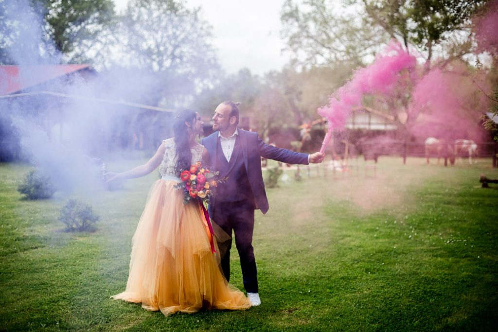 Mariés s’embrassant entourés de fumée colorée lors d’un shooting mariage artistique