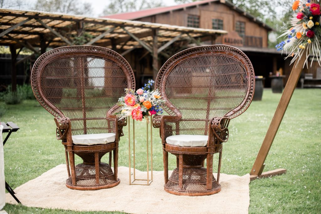 Décoration mariage avec fauteuils en rotin et composition florale dans un jardin