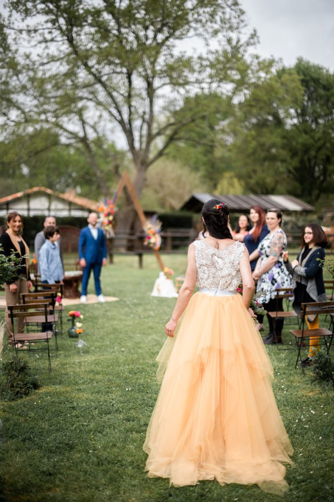 mariée de dos remontant l'allée de la cérémonie laïque