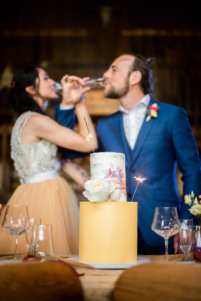 couple qui boivent du champagne devant leur wedding cake