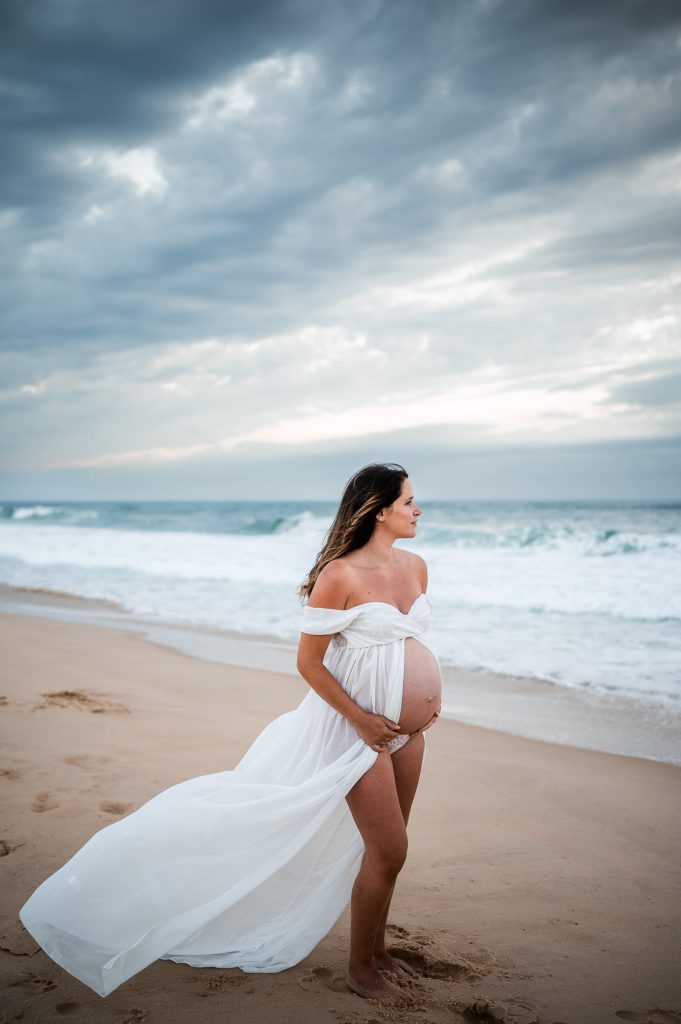 femme enceinte en robe blanche sur la plage pour une séance grossesse à Mimizan dans les Landes