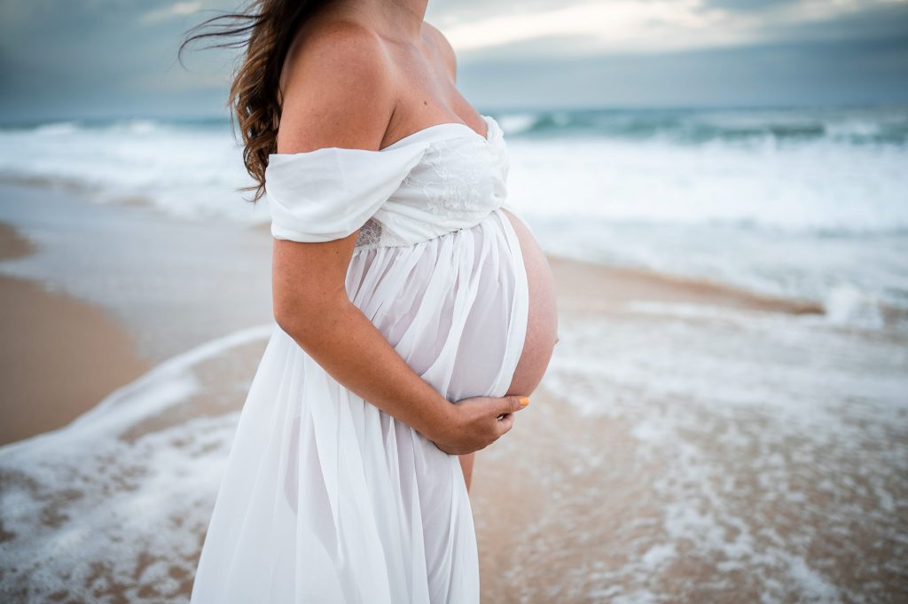 détail ventre rond en robe blanche au bord de l’océan séance grossesse Mimizan
