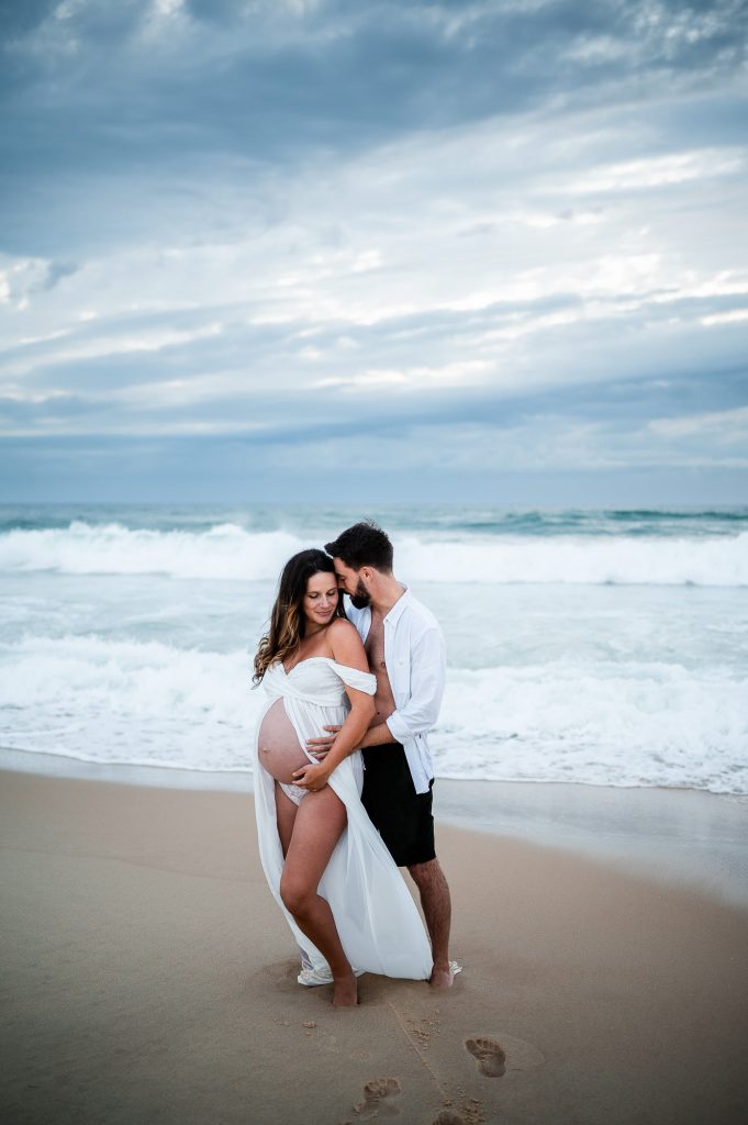 couple enlacé sur la plage pendant une séance photo grossesse à Mimizan dans les Landes