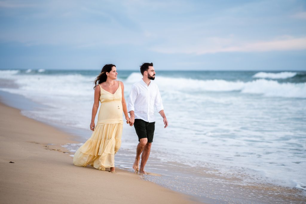 couple marchant sur la plage lors d’une séance grossesse à Mimizan dans les Landes