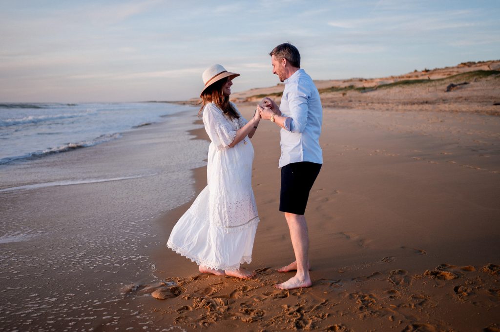 femme enceinte marchant sur la plage avec son compagnon séance photo grossesse
