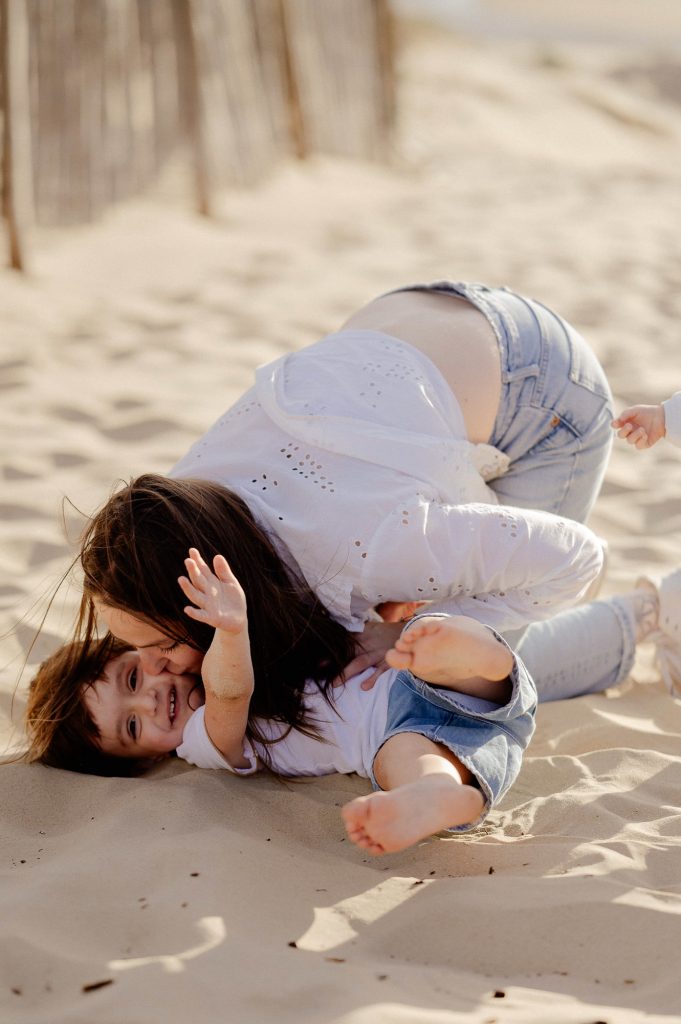maman jouant avec son bébé sur la plage à Mimizan au coucher du soleil
