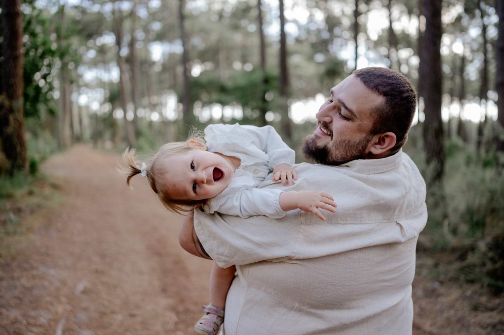 papa portant son bébé lors d’une séance photo famille en forêt à Mimizan