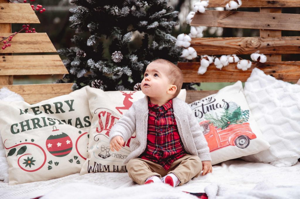 Enfant dans un décor de Noël en bois lors d’une séance photo