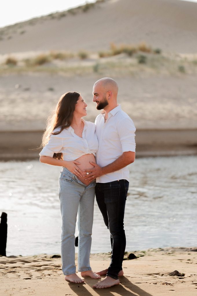Couple en séance photo grossesse au coucher du soleil sur la plage dans les Landes