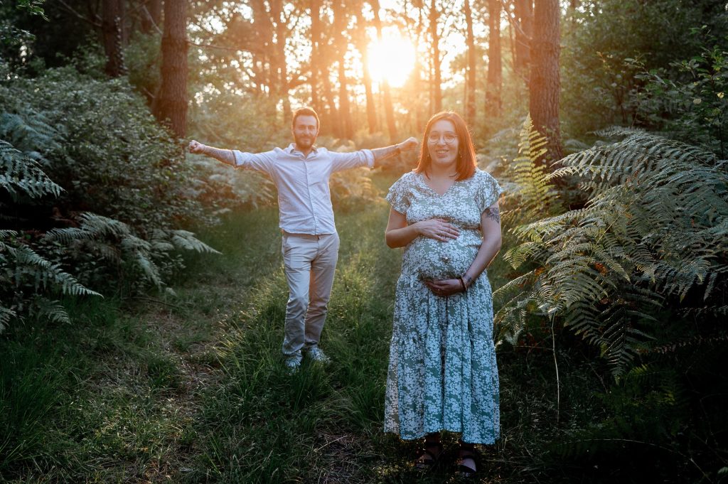 Couple souriant en séance photo grossesse en forêt dans les Landes