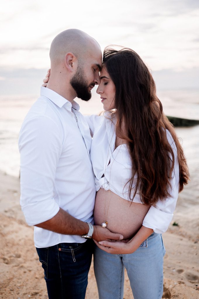 Femme enceinte avec son partenaire sur la plage au coucher du soleil dans les Landes