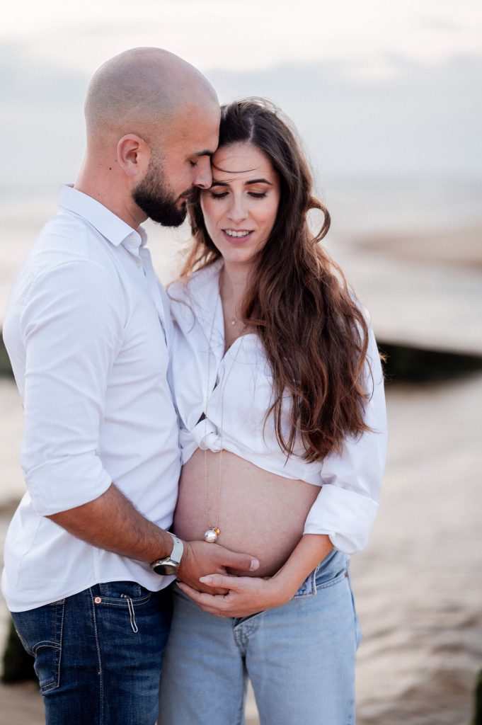 Femme enceinte avec son partenaire sur la plage au coucher du soleil dans les Landes