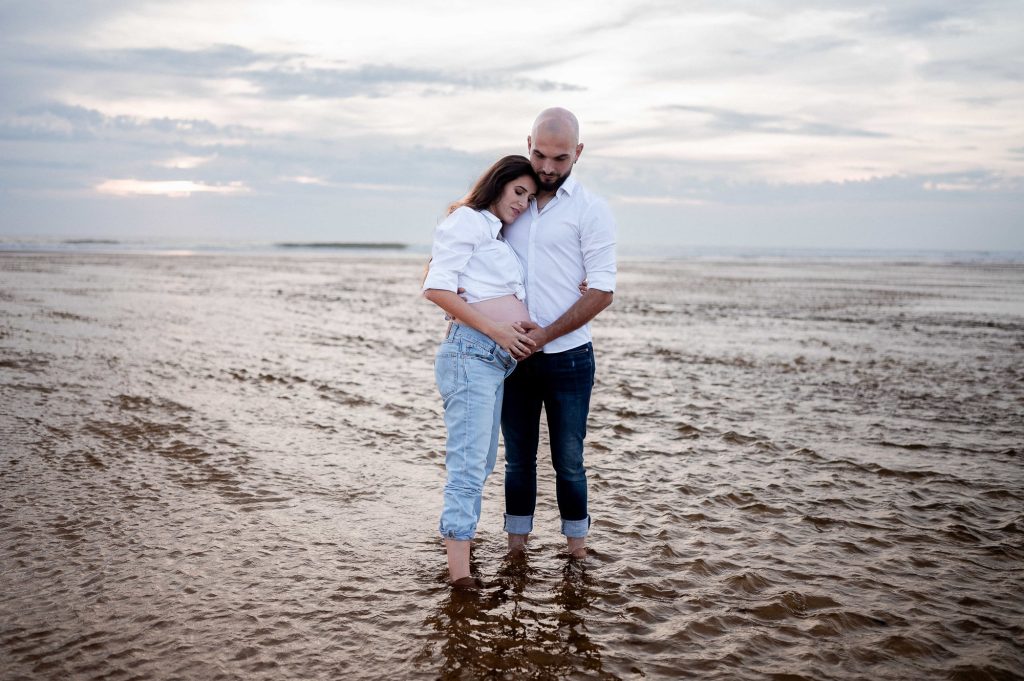 Femme enceinte avec son partenaire sur la plage au coucher du soleil dans les Landes