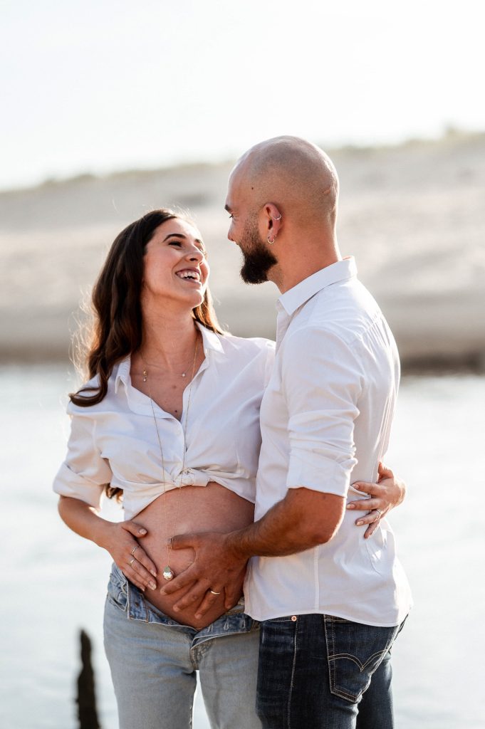 Couple en séance photo grossesse au coucher du soleil sur la plage dans les Landes