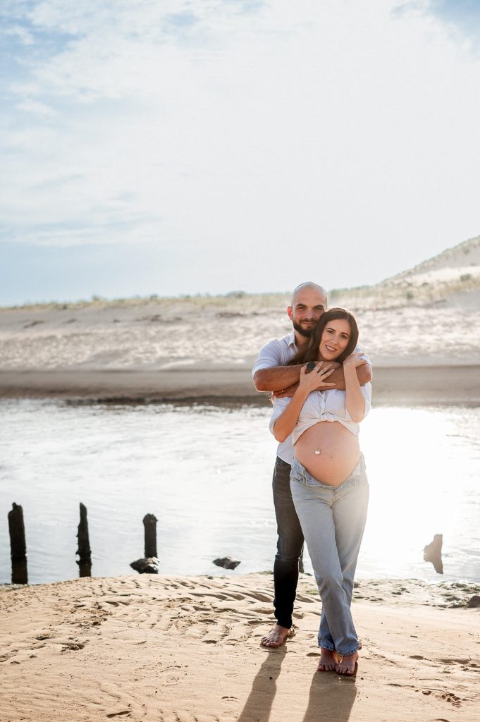 Femme enceinte avec son partenaire sur la plage au coucher du soleil dans les Landes