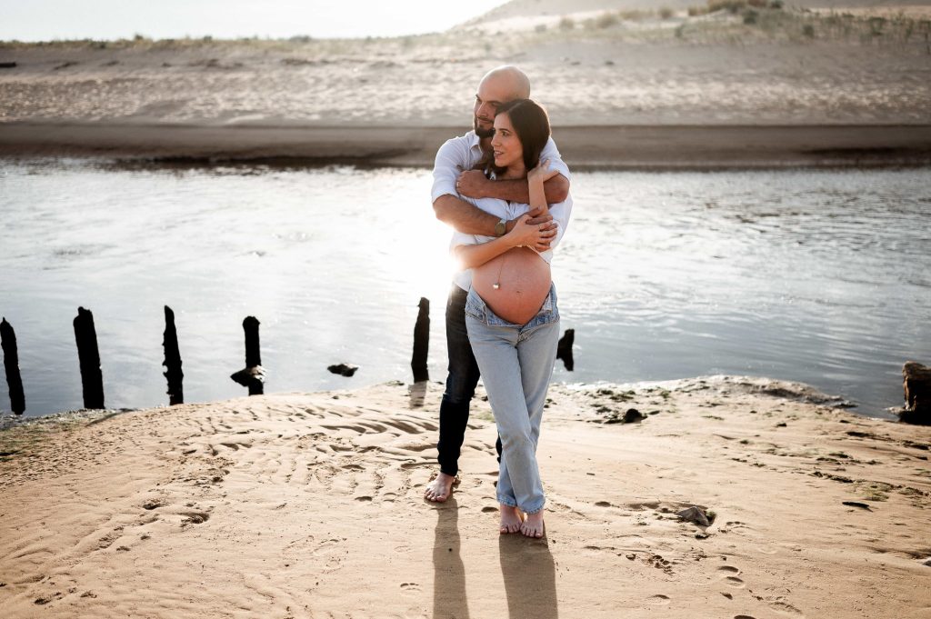 Femme enceinte avec son partenaire sur la plage au coucher du soleil dans les Landes