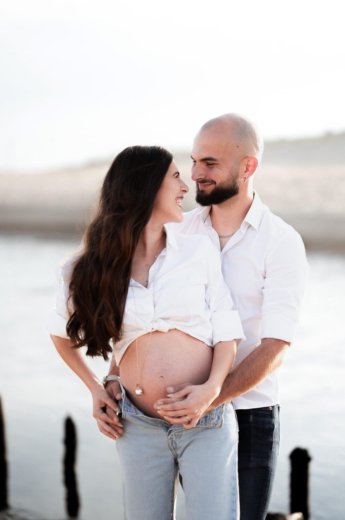 Femme enceinte avec son partenaire sur la plage au coucher du soleil dans les Landes