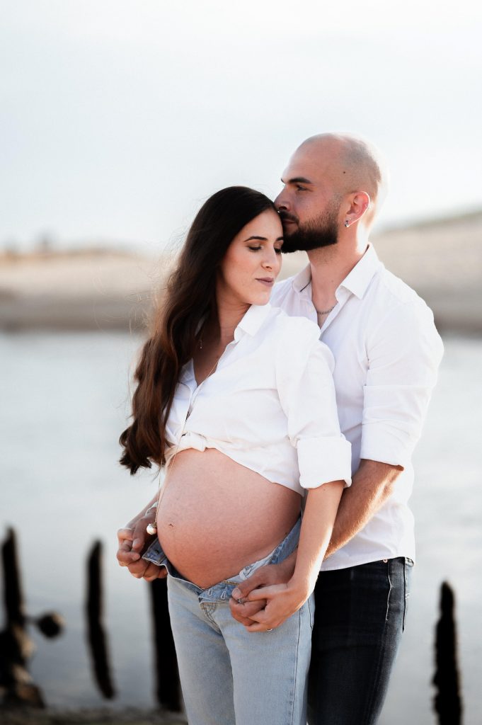 Femme enceinte avec son partenaire sur la plage au coucher du soleil dans les Landes