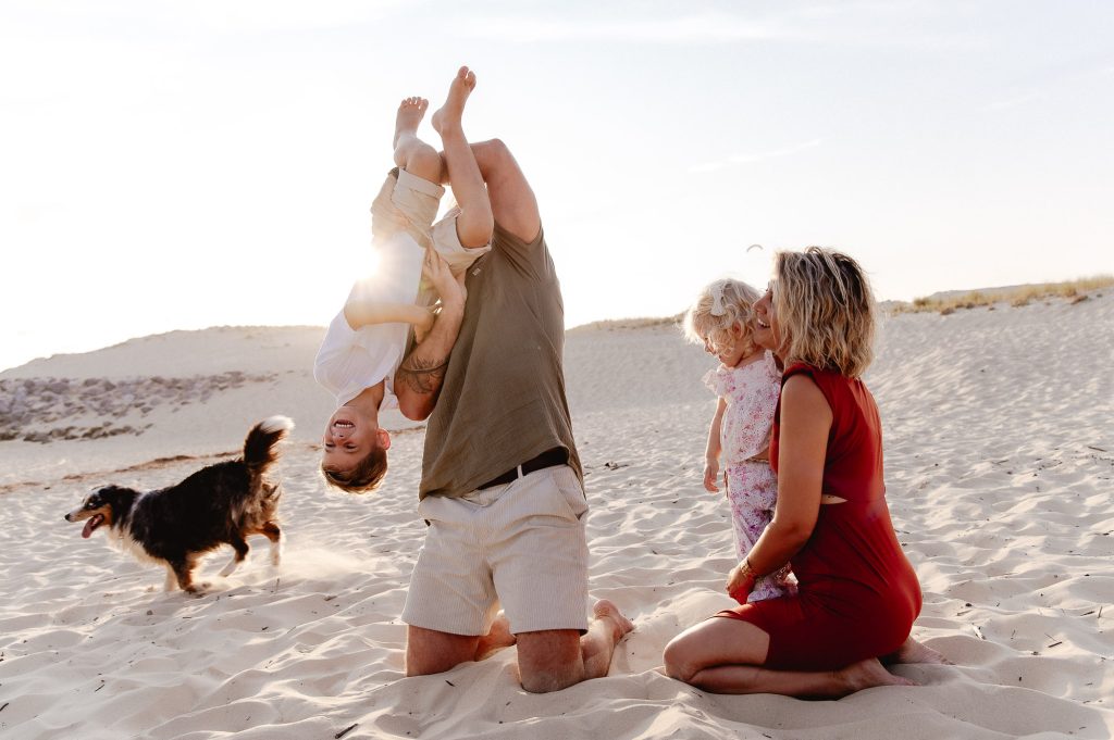 papa tenant son enfant par les pieds en séance photo famille dans les landes