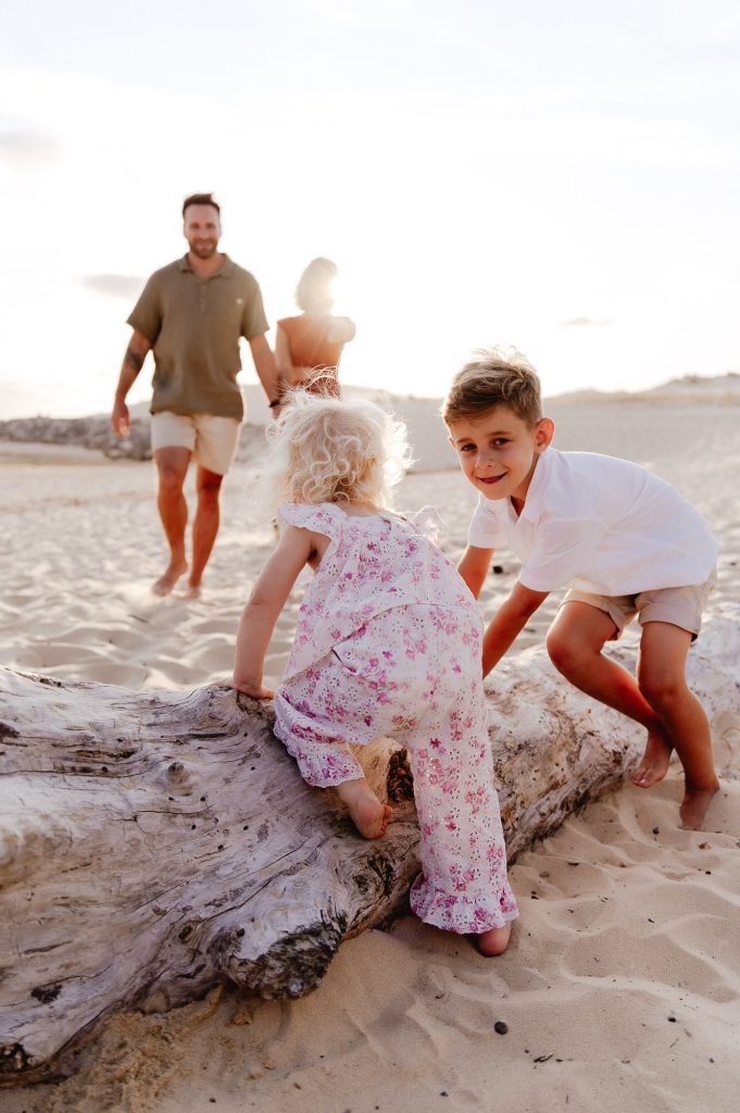 enfants sur un tronc de bois flotté à Contis plage