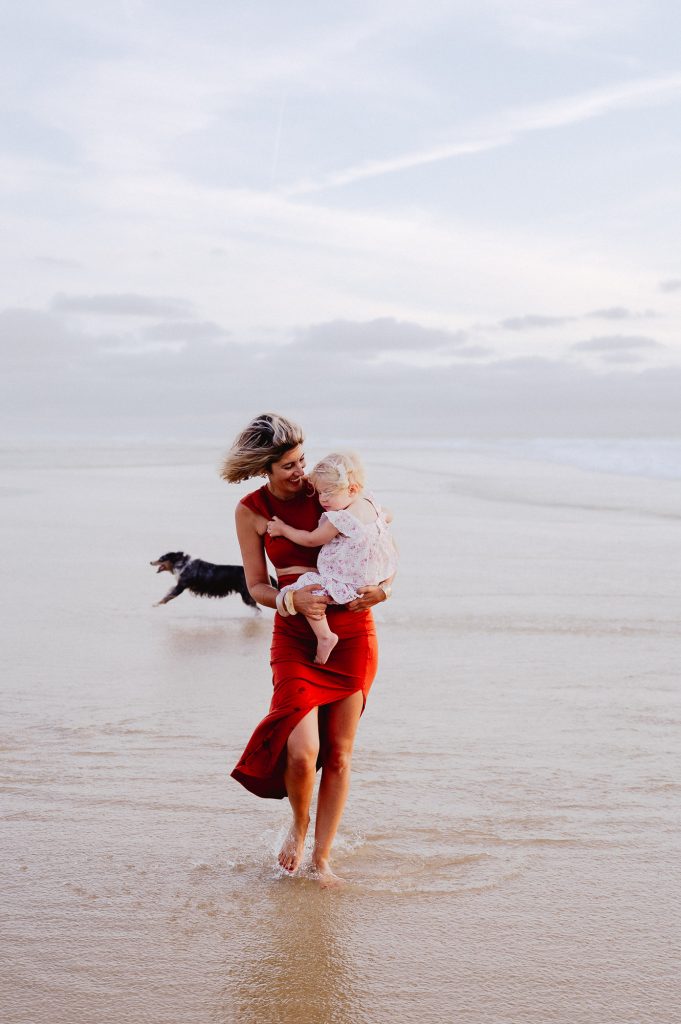 maman marchant avec sa fille dans les bras sur la plage à contis