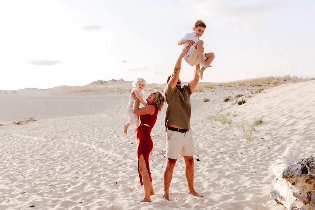 parents portant leurs enfants à bout de bras sur la plage
